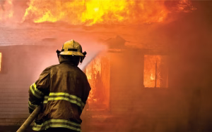 A fireman putting out a house fire with a hose