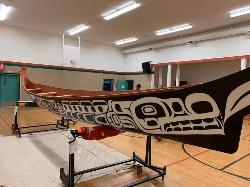 A carved K’ómoks First Nation canoe in a gymnasium