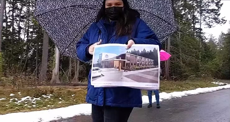 A person holding a large architectural rendering of a modern building outdoors