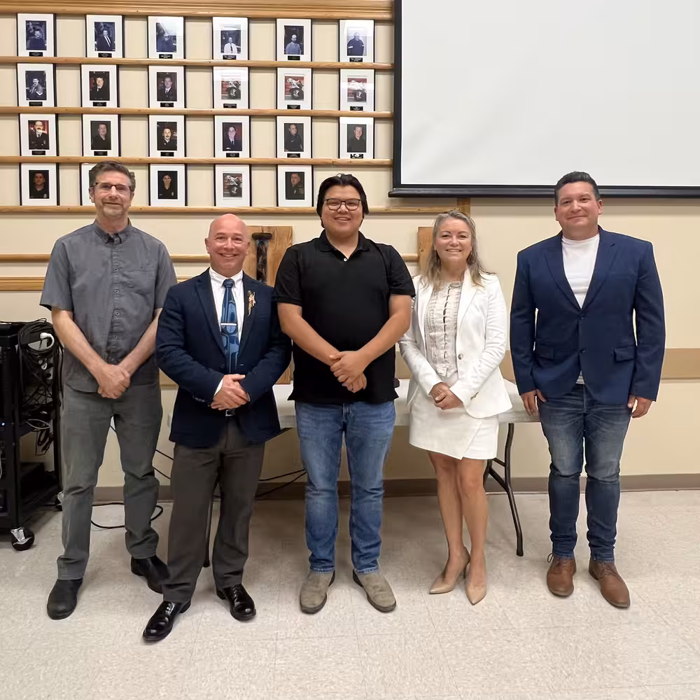 Five Officials Posing in Front of Community Portrait Wall