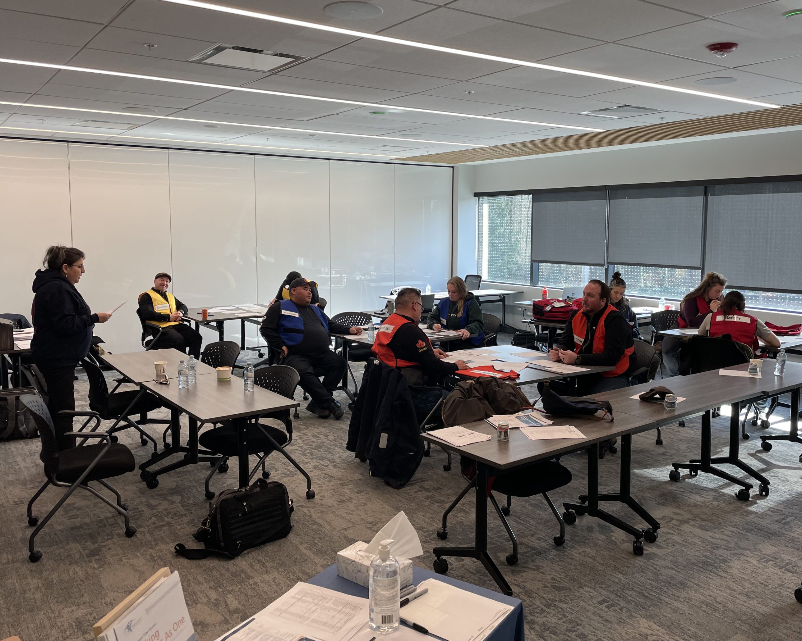 People in a training room wearing safety vests participate in a tabletop emergency preparedness exercise.